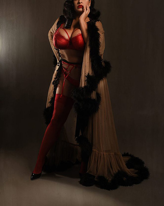 Athens Dominatrix seated in latex and thigh-high boots ready to take professional session bookings